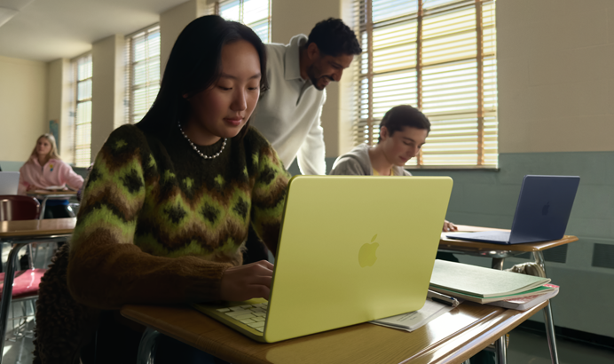 Eine Schülerin verwendet ein MacBook Neo in der Farbe Zitrus, das nicht am Strom angeschlossen ist, in einem Klassenzimmer